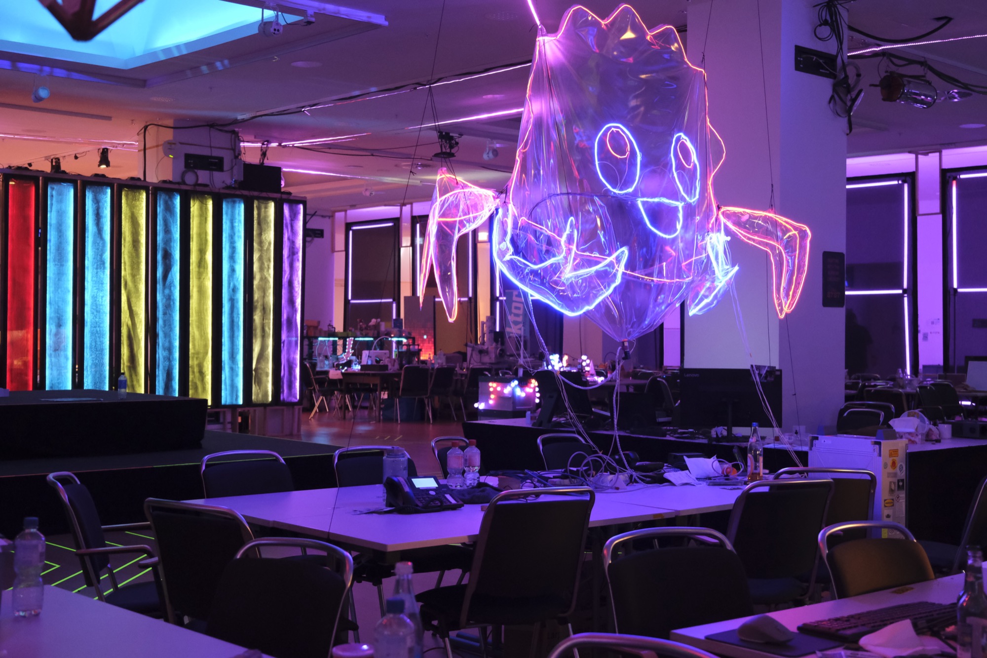 A large inflatable Ferris the crab traced in glowing wire, hanging over a hall at a hacker conference