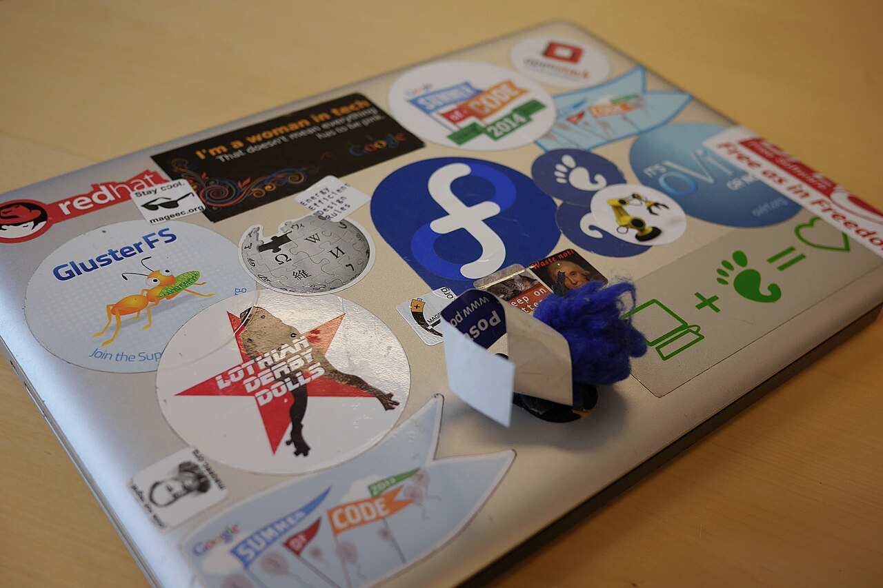 A laptop covered in free software stickers at a GUADEC conference