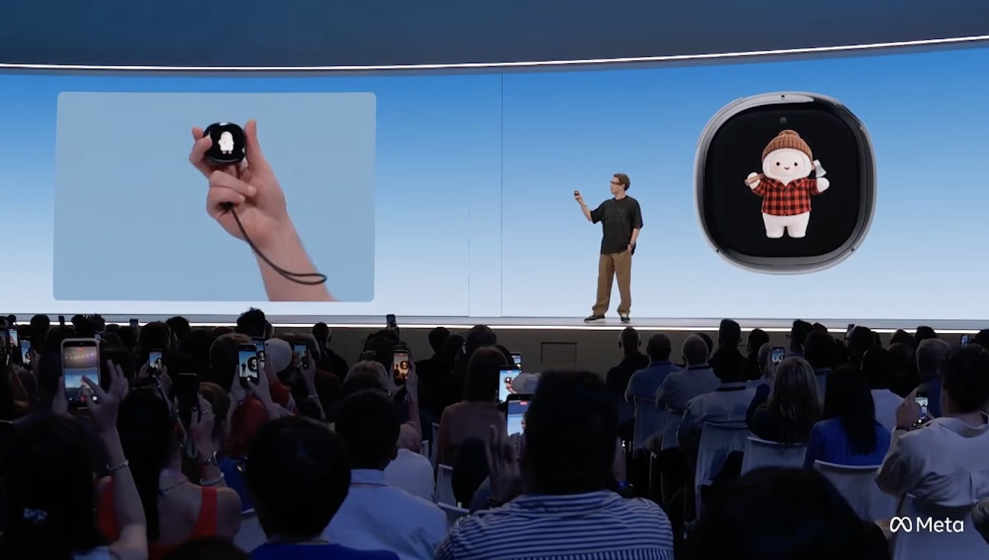 Mark Zuckerberg on the Connect stage next to a large render of the Muse Charm, with Jolly on its screen wearing a red plaid outfit